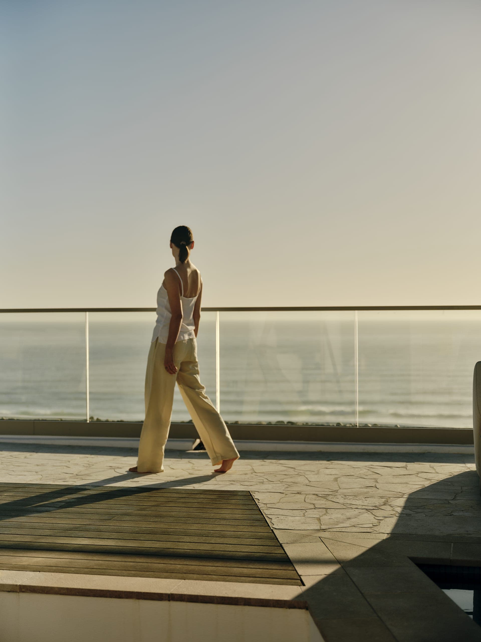 A resident pauses on a private terrace at golden hour, ocean beyond.